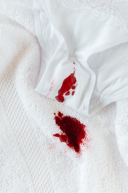 Close-up image of a white textile surface, likely bedding or a towel, showing a bloodstain and a small piece of white fabric with a red bloodstain on it. The surface appears soft and textured, with a clean, well-lit environment highlighting the contrast between the white fabric and the dark red stain. This visual detail emphasizes the importance of stain removal and surface cleaning services. Carpet Cleaners Harrow offers emergency stain removal and deep cleaning solutions to restore hygiene and cleanliness to domestic surfaces, ensuring thorough sanitisation and maintenance of living spaces. The focus is on the stain's visibility, displaying the need for professional cleaning to achieve pristine results in residential environments, particularly when addressing urgent messes requiring same-day service.
